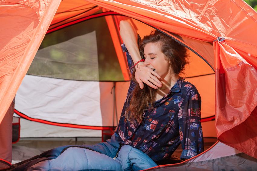 Frau gähnt im Zelt - bequem schlafen im Zelt bedarf einiger Vorbereitung 