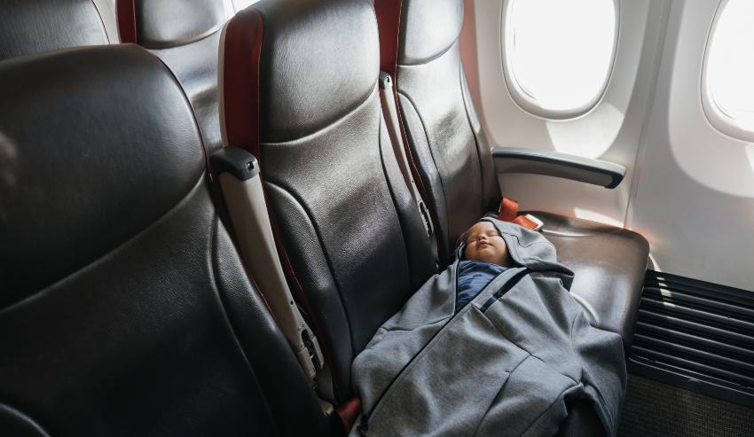 Kind schläft ausgestreckt im Flugzeug