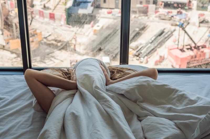 Frau schläft am Fenster; im Hintergrund ist eine Baustelle zu sehen
