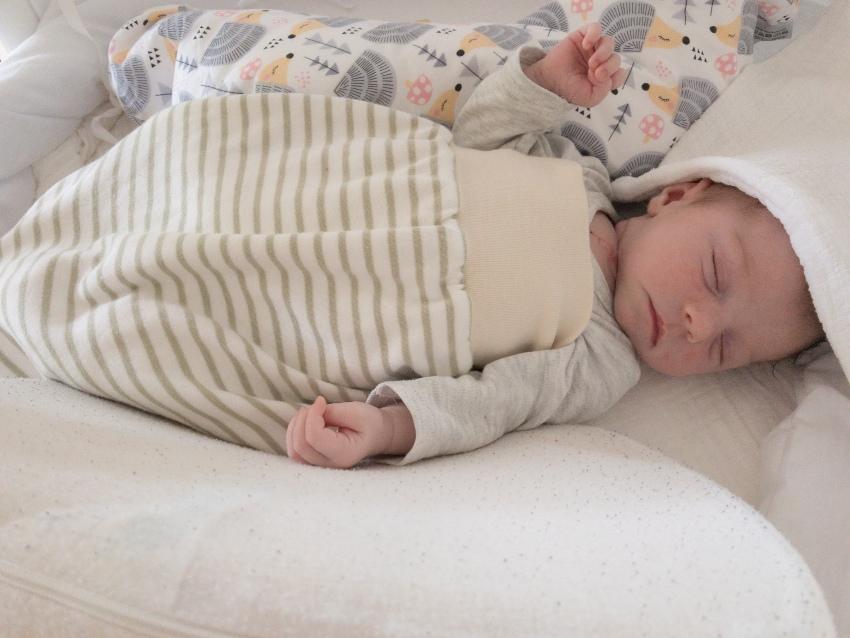 Neugeborenes Kind mit Babyschlafsack - Bettdecke
