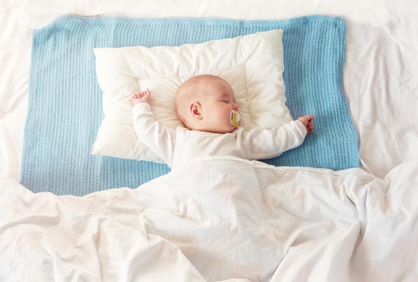 Baby mit Bettdecke und Babykissen