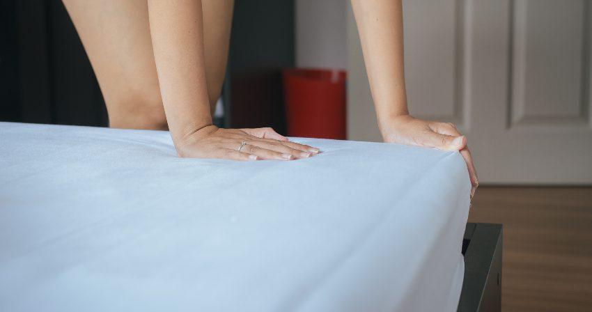 Frau zieht Bettlaken aufs Bett