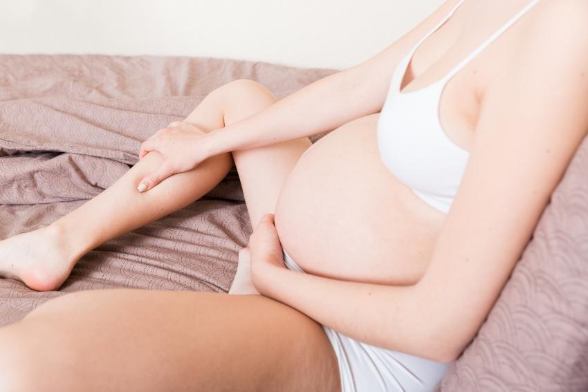 Schwangere Frau fasst sich an die Wade - Nächtliche Wadenkrämpfe sind in der Regel harmlos