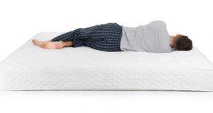 Mann liegt im Bett - Rückenschonende Matratzen