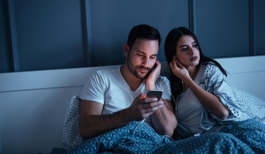 Junges Paar hört Audiobuch im Bett