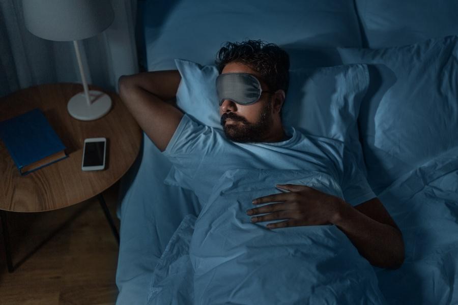 Mann schläft mit Schlafmaske - Erste-Nacht-Effekt bekämpfen