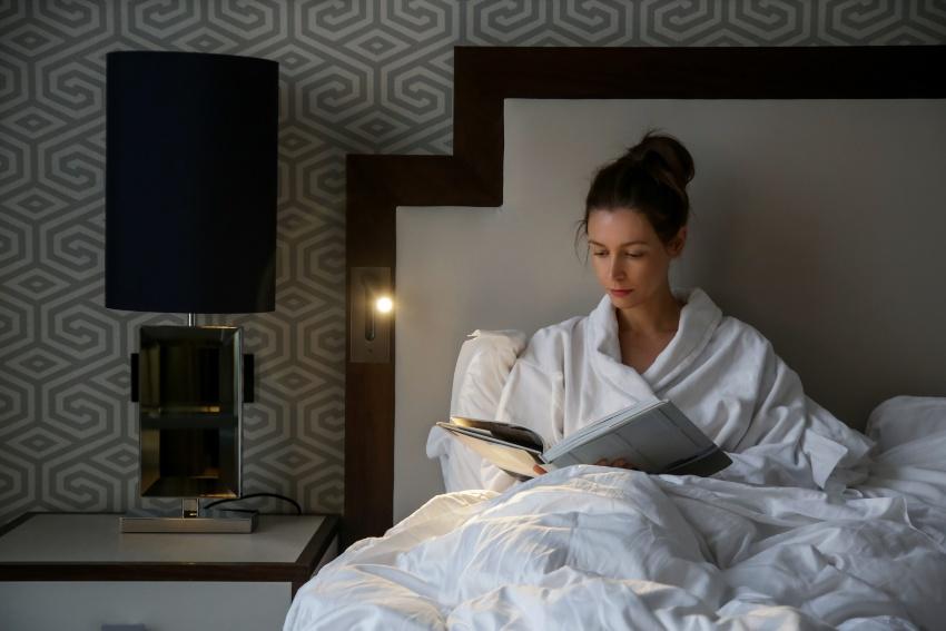 Junge Frau liest abends im Bett - Die ideale Schlafenszeit