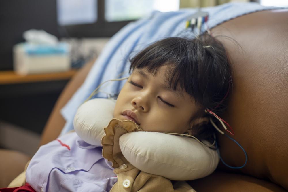 Mädchen schläft, an Elektroden angeschlossen, um Hirnströme zu messen
