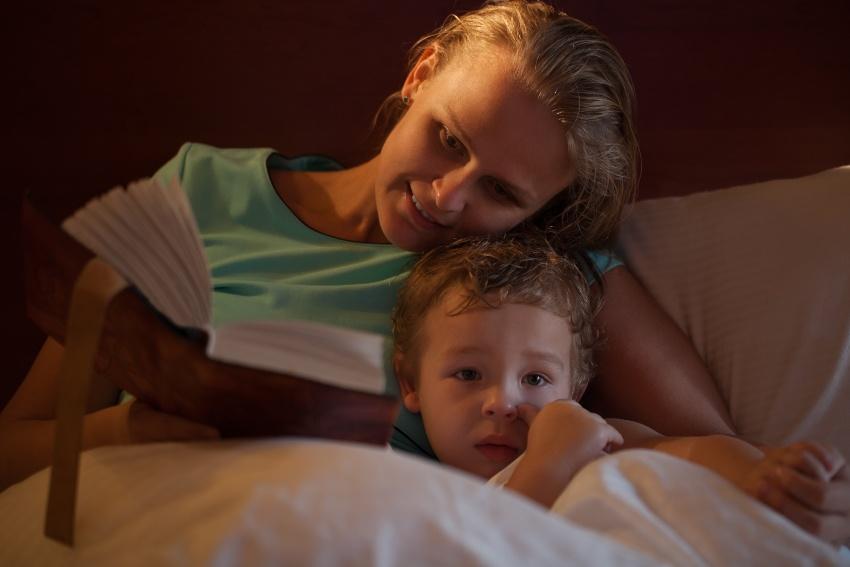 Mutter liest Sohn im Bett eine Geschichte vor - Besser durchschlafen durch 