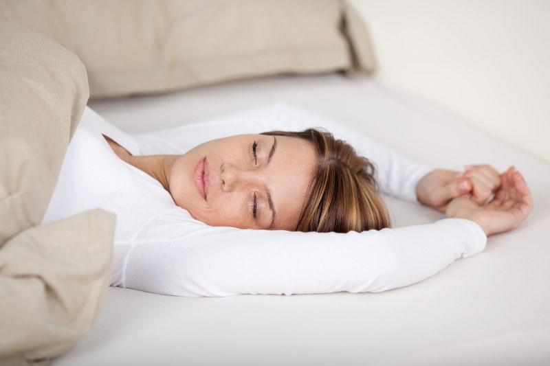 Eine Frau streckt sich auf der Matratze, während sie schläft 