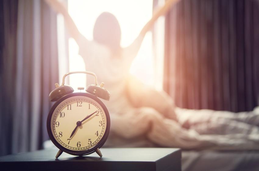 Junge Frau streckt sich morgens vorm Fenster - Morgens schneller wach werden