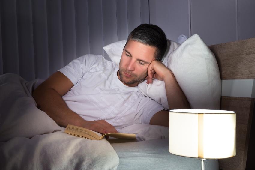 Mann liest abends Buch im Bett