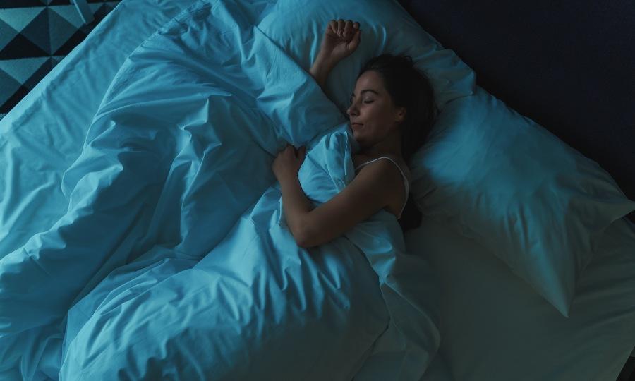 Junge Frau schläft im Bett + Besser schlafen nach der Nachtschicht