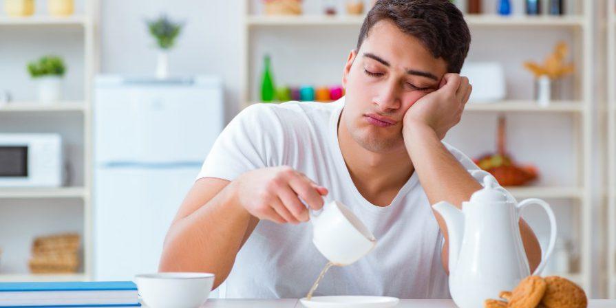 Junger Mann müde beim Frühstück - Schlafrhythmus umstellen