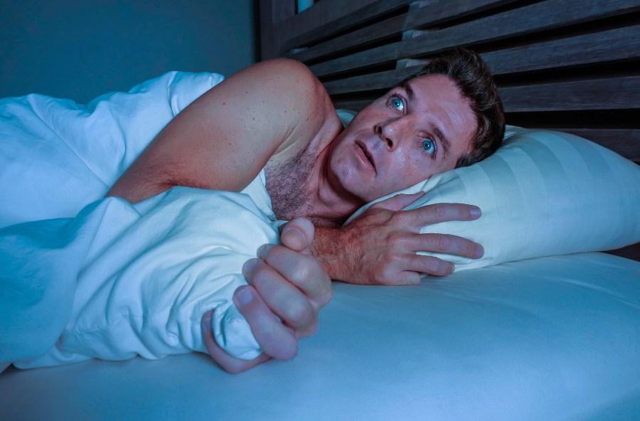 Mann im Bett, wirkt erschrocken - Pavor Nocturnus