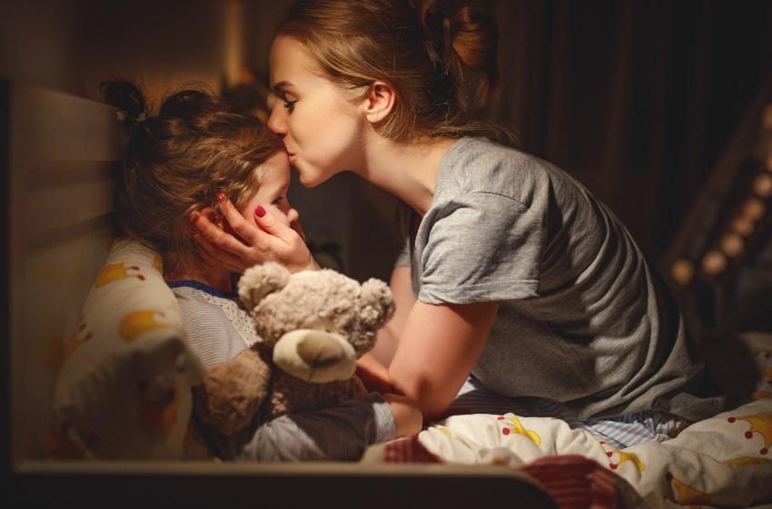 Mutter küsst Kind vor dem Schlafengehen