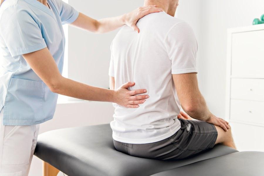 Orthopädin behandelt Patient am Rücken - vielleicht ist die Matratze zu hart 
