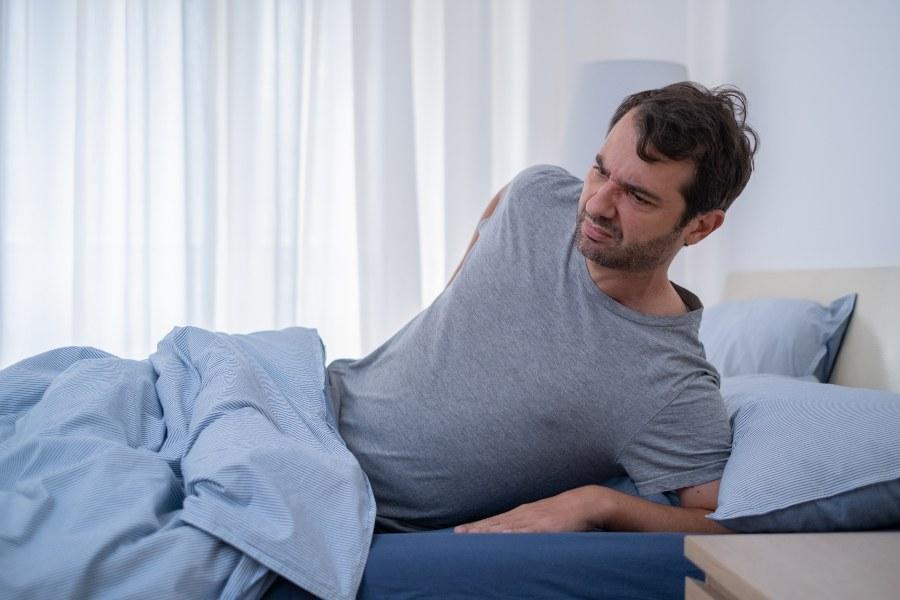 Mann wacht auf mit Schmerzen im Lendenbereich - Matratze zu hart kann eine Ursache sein