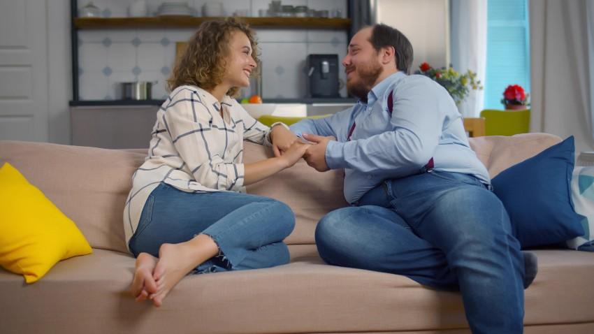 Paar sitzt auf Couch - Mann deutlich schwerer als Frau