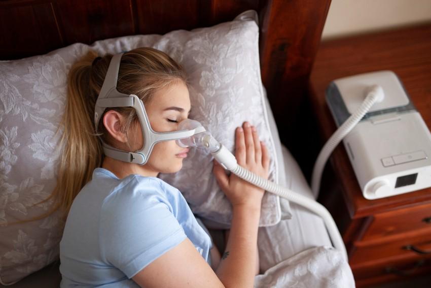 Junge Frau schläft mit Maske - Schlafapnoe - Schnarchprobleme