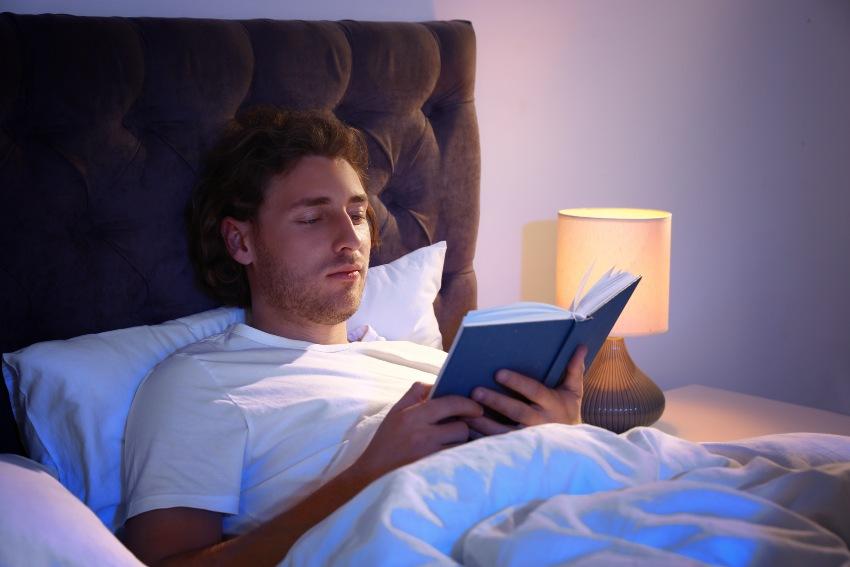 Junger Mann liest im Bett