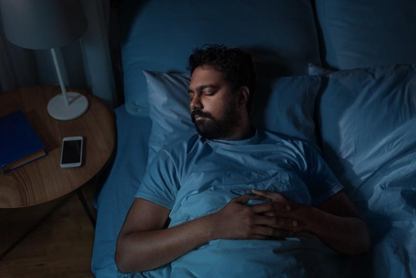 Mann schläft bei minimaler Helligkeit - Im Dunkeln schlafen oder im Hellen?