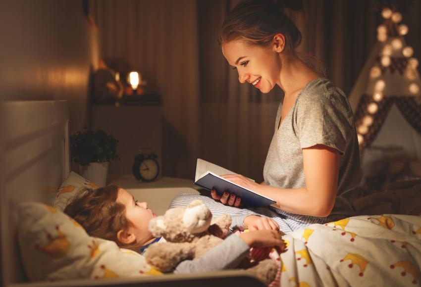 Mutter liest Kind eine Gute-Nacht-Geschichte vor - Schlafbedarf von Kleinkindern